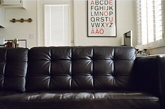 Black tufted leather sofa in front of a wall with an alphabet poster