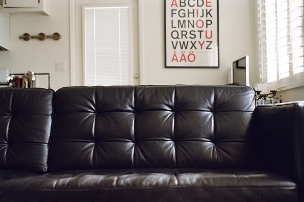 Black tufted leather sofa in front of a wall with an alphabet poster — upscaled by Nano Banana 2
