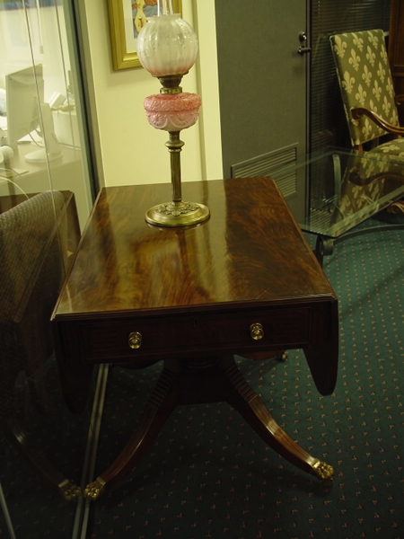 Mahogany drop-leaf table with a brass oil lamp on a green carpet — upscaled by Nano Banana 2
