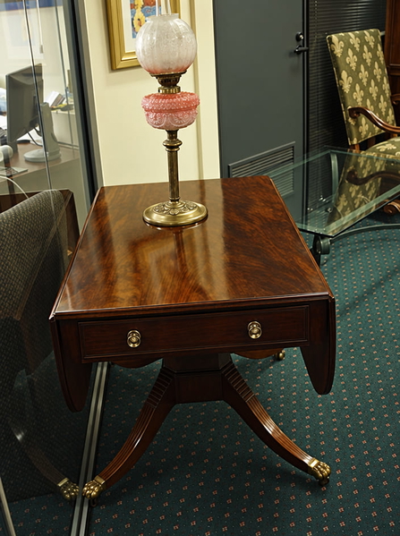 Mahogany drop-leaf table with a brass oil lamp on a green carpet — upscaled by GPT Image 2.5