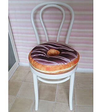 White bentwood chair with a doughnut-shaped cushion against a striped wall