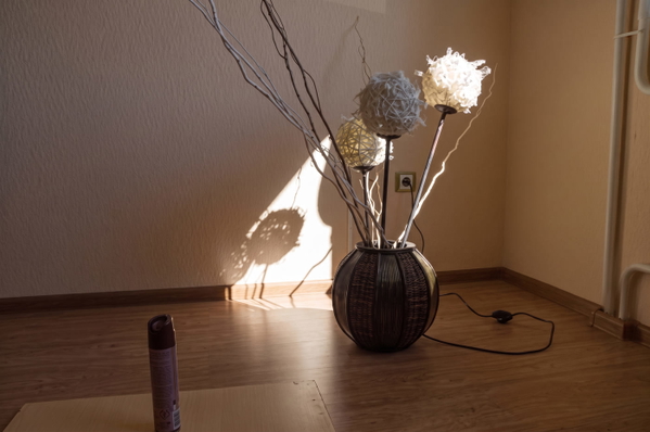 Vase of dried branches casting a shadow in a sunlit corner of a room — upscaled by Nano Banana 2