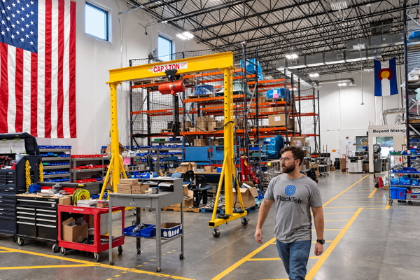 Fabrication workshop with a yellow gantry crane, storage racking and a US flag on the wall — upscaled by GPT Image 2.5