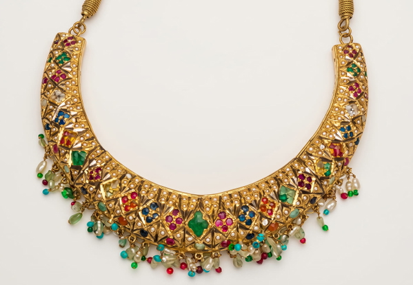 Gold collar necklace set with coloured stones on a pale background — upscaled by Nano Banana 2