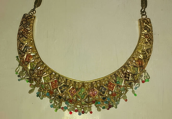 Gold collar necklace set with coloured stones on a pale background — upscaled by GoStudio Pro