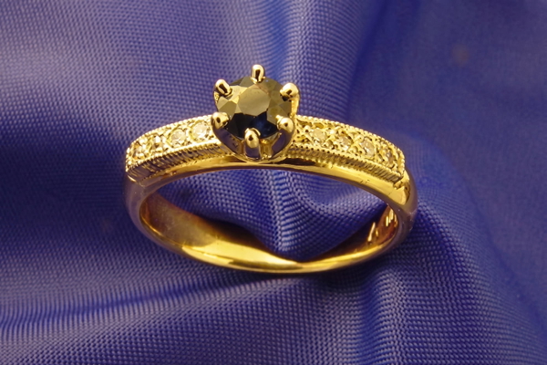 Gold ring with a dark faceted stone resting on blue satin — upscaled by Nano Banana 2