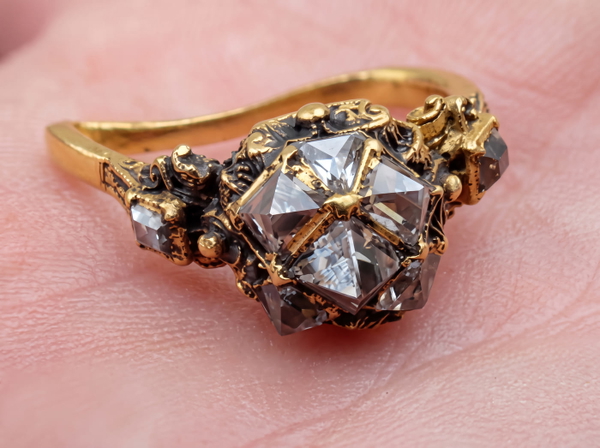 Rough uncut diamond set in a gold ring, held on a fingertip — upscaled by GoStudio Advanced