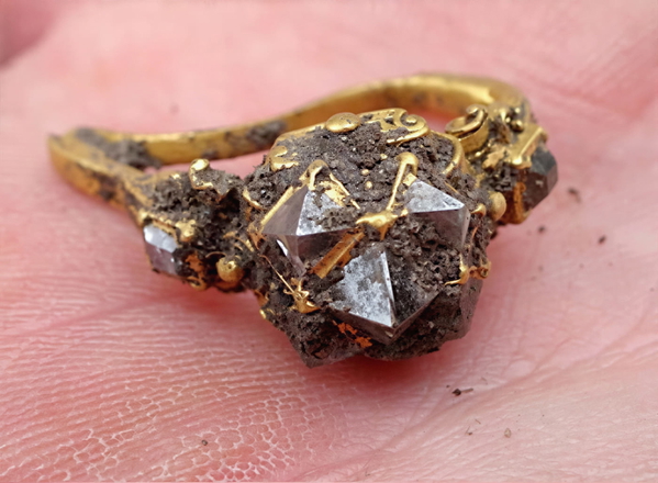 Rough uncut diamond set in a gold ring, held on a fingertip — upscaled by GoStudio Lite