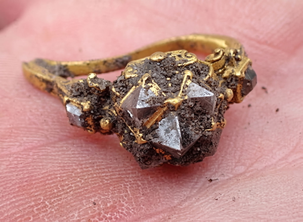 Rough uncut diamond set in a gold ring, held on a fingertip — upscaled by Nano Banana 2