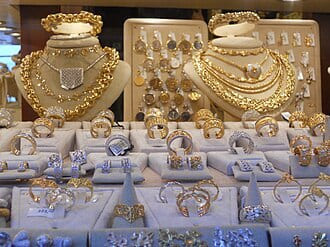 Shop display of gold necklaces and rings on white stands