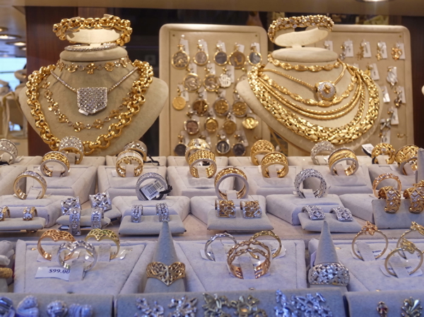 Shop display of gold necklaces and rings on white stands — upscaled by Nano Banana 2