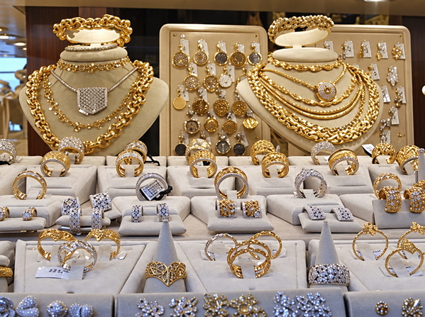 Shop display of gold necklaces and rings on white stands — upscaled by GPT Image 2.5