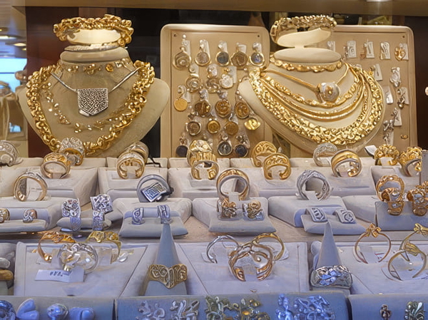 Shop display of gold necklaces and rings on white stands — upscaled by GoStudio Pro