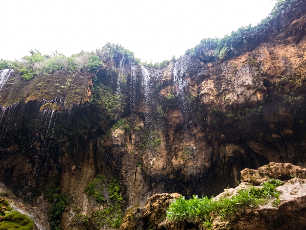 Waterfall over a dark rock face into a gorge with green vegetation — upscaled by Nano Banana 2