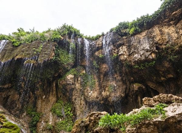 Waterfall over a dark rock face into a gorge with green vegetation — upscaled by GPT Image 2.5