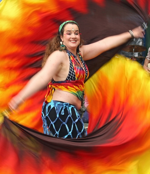Festival dancer with an arm raised, swirling red and orange fans behind her — upscaled by Nano Banana 2