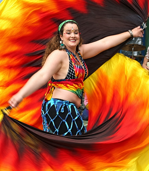 Festival dancer with an arm raised, swirling red and orange fans behind her — upscaled by GPT Image 2.5