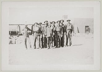 Archive print of a row of men standing outside a building, mounted on card
