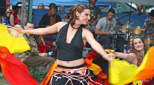 Woman in a black halter top dancing with yellow fans in front of a seated crowd — upscaled by GoStudio Advanced