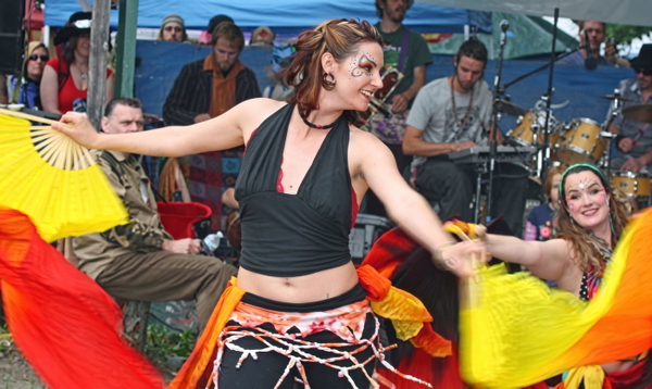 Woman in a black halter top dancing with yellow fans in front of a seated crowd — upscaled by Nano Banana 2