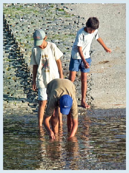 Three boys paddling in shallow water at the foot of a stone slipway — upscaled by Nano Banana 2