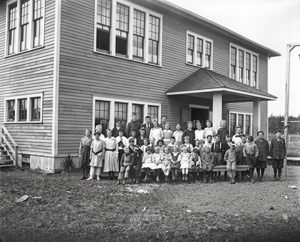 Black-and-white school photograph of pupils lined up in front of a two-storey clapboard school — upscaled by GoStudio Advanced