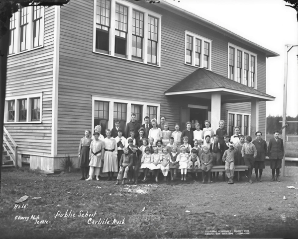 Black-and-white school photograph of pupils lined up in front of a two-storey clapboard school — upscaled by GoStudio Lite