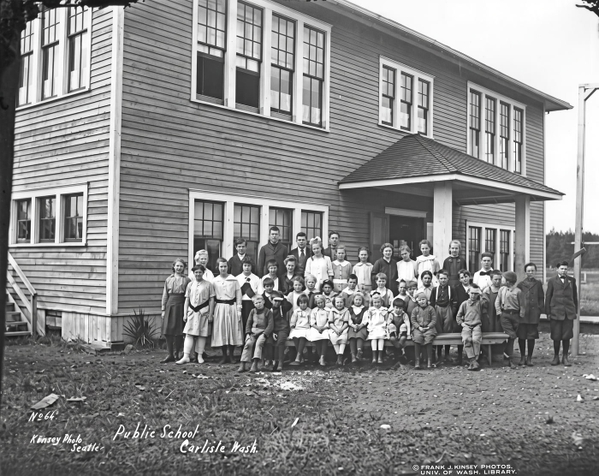 Black-and-white school photograph of pupils lined up in front of a two-storey clapboard school — upscaled by Nano Banana 2