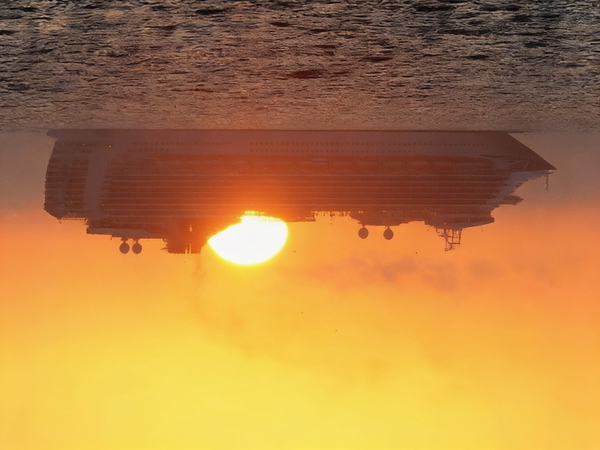 Cruise ship on a hazy sea at sunset, the sun sitting on the waterline behind it — watermark removed by GoStudio Advanced