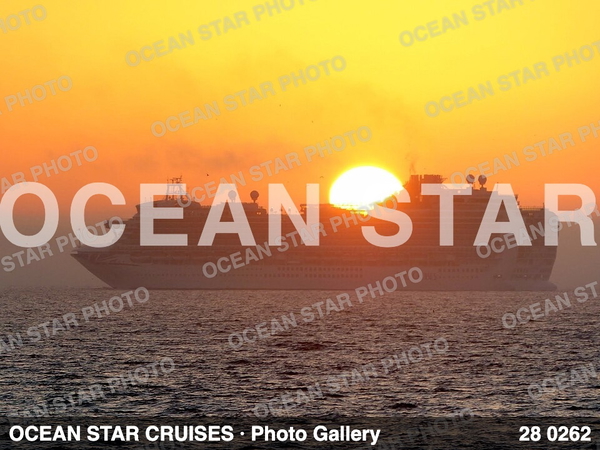 Cruise ship on a hazy sea at sunset, the sun sitting on the waterline behind it