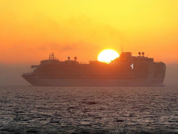 Cruise ship on a hazy sea at sunset, the sun sitting on the waterline behind it — watermark removed by GoStudio Lite