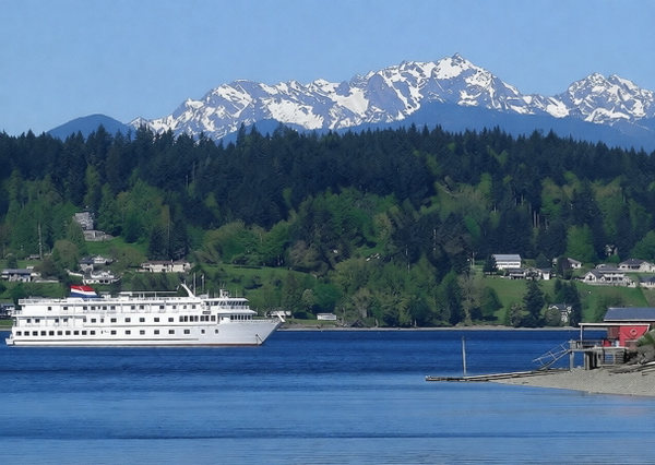 Small white cruise ship on blue water below forested hills and snow-capped mountains — watermark removed by GoStudio Pro