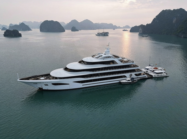Aerial view of a white superyacht moored among limestone karsts at dusk — watermark removed by GoStudio Advanced