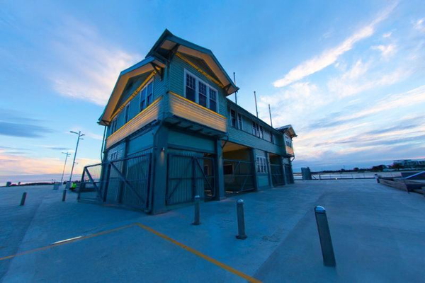 Blue and yellow timber pier building under a wide evening sky — watermark removed by GoStudio Lite