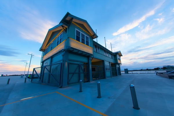 Blue and yellow timber pier building under a wide evening sky — watermark removed by GoStudio Pro