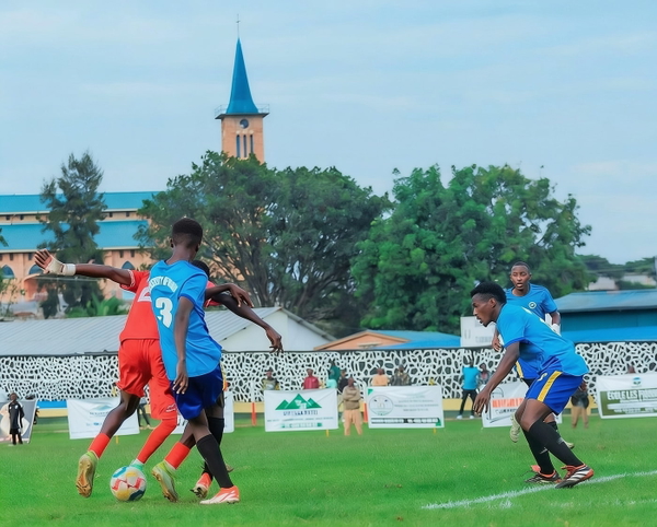 Two football players challenging for the ball in front of a stand and a church spire — watermark removed by GoStudio Advanced