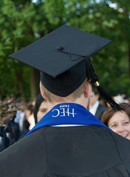 Graduate seen from behind in a mortarboard and blue stole, crowd beyond — watermark removed by GoStudio Advanced