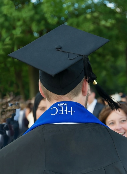 Graduate seen from behind in a mortarboard and blue stole, crowd beyond — watermark removed by GoStudio Pro