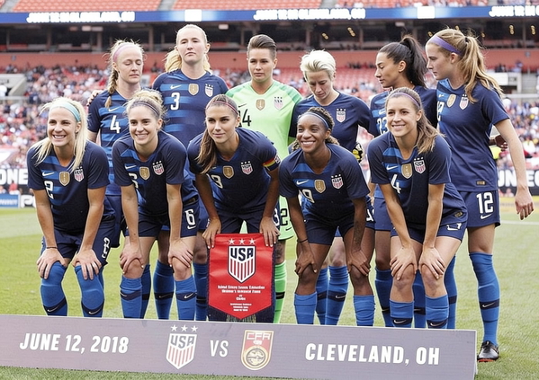 Women’s football team in navy kit lined up before a match, with a match-day banner — watermark removed by GoStudio Advanced