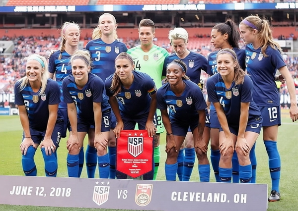 Women’s football team in navy kit lined up before a match, with a match-day banner — watermark removed by GoStudio Pro