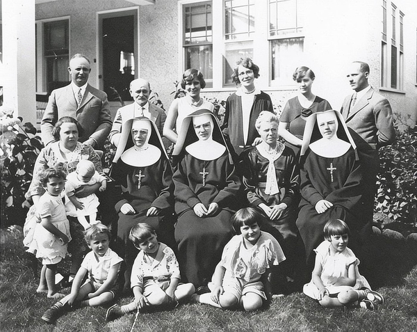 Black-and-white group photo of nuns, adults and children outside a building — watermark removed by GoStudio Advanced