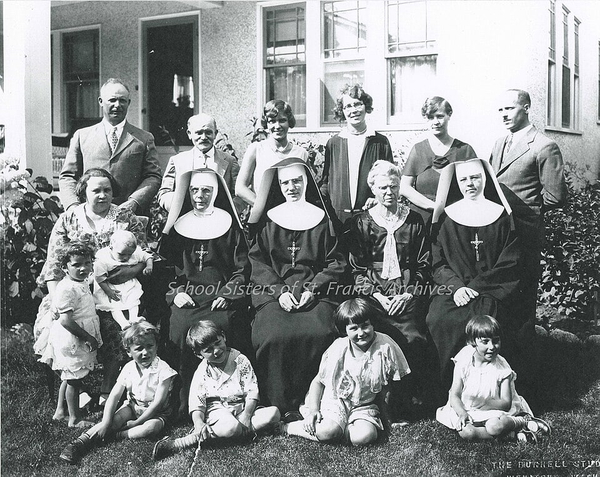 Black-and-white group photo of nuns, adults and children outside a building