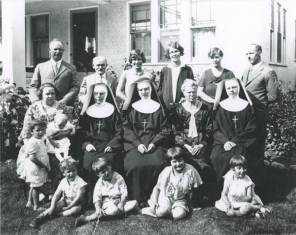 Black-and-white group photo of nuns, adults and children outside a building — watermark removed by GoStudio Lite
