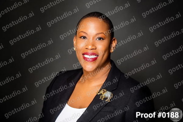 Woman in a navy blazer with an elephant brooch, smiling, on a dark backdrop