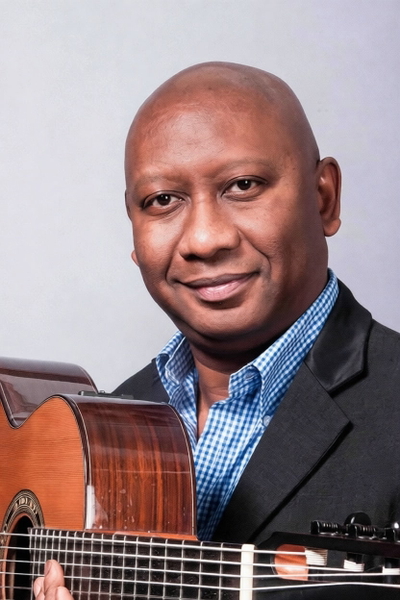 Smiling man in a checked shirt and dark jacket holding a guitar — watermark removed by GoStudio Pro
