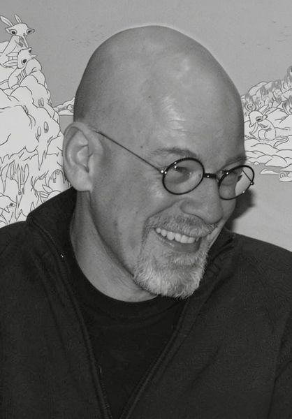 Black-and-white portrait of a bald man in round glasses, laughing, in front of a line-drawing mural — watermark removed by GoStudio Advanced