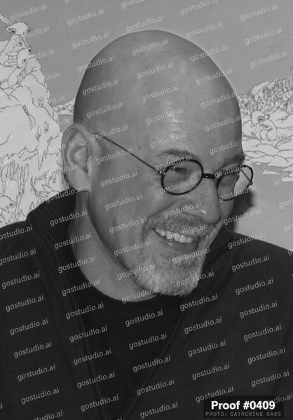 Black-and-white portrait of a bald man in round glasses, laughing, in front of a line-drawing mural