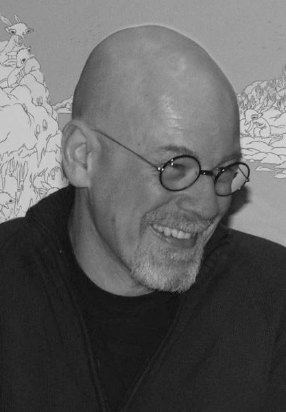 Black-and-white portrait of a bald man in round glasses, laughing, in front of a line-drawing mural — watermark removed by GoStudio Lite