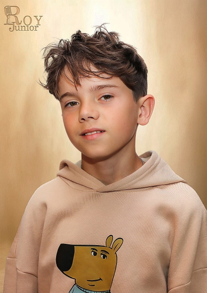 Studio portrait of a boy in a beige hoodie with a cartoon dog on it
