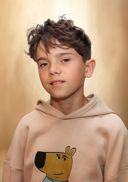 Studio portrait of a boy in a beige hoodie with a cartoon dog on it — watermark removed by GoStudio Lite